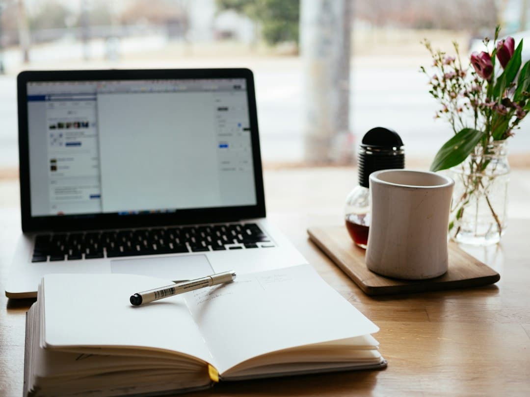 A laptop next to an open notebook on a desk