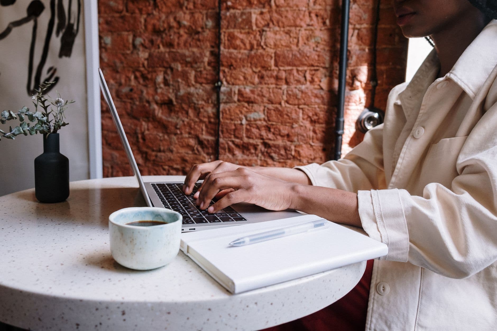 A woman working on a laptop with coffee in a cafe