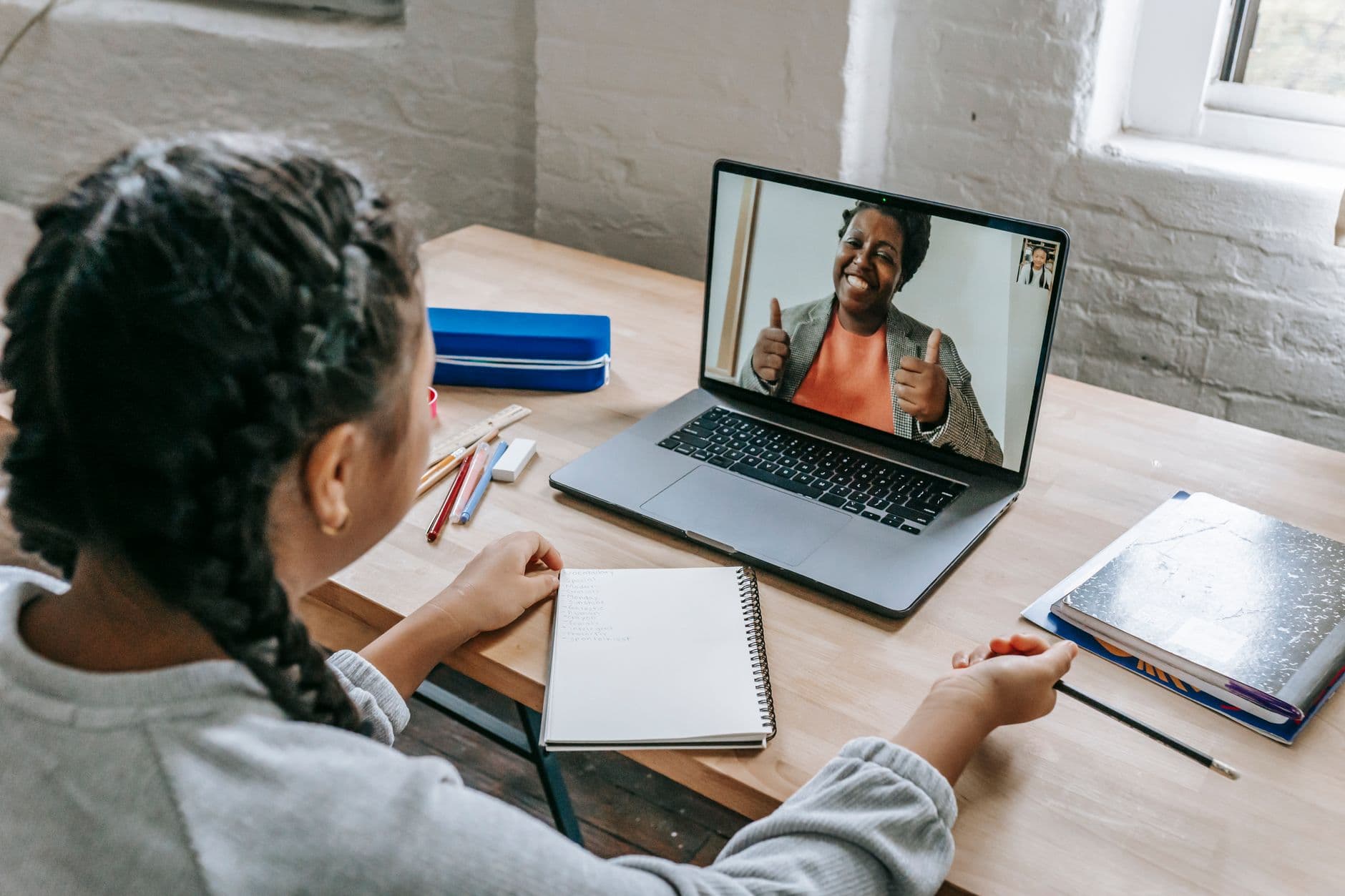 A girl on a video call with her tutor while studying on a laptop