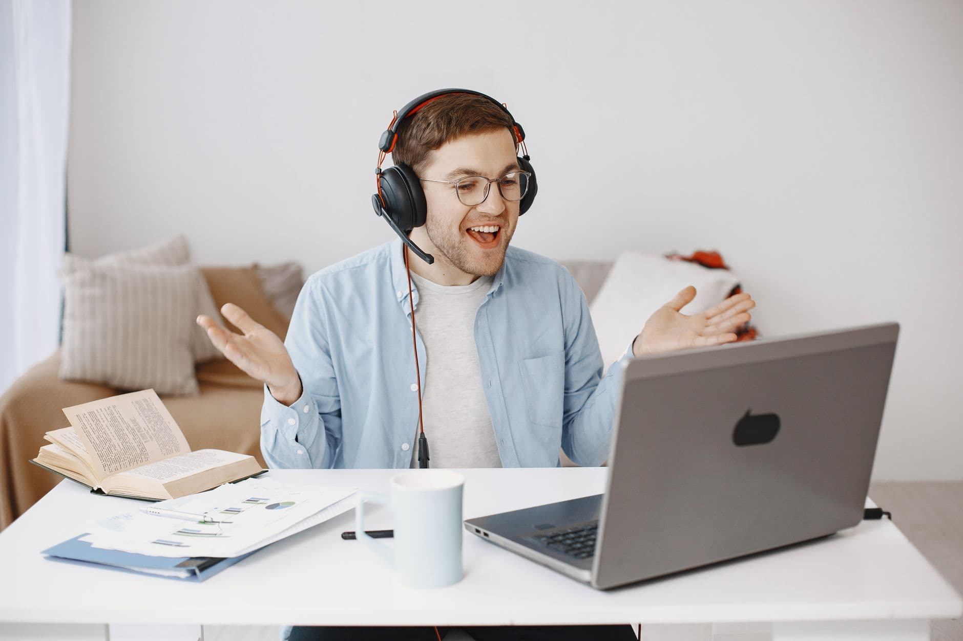 A smiling man in headphones on a video call in his home office