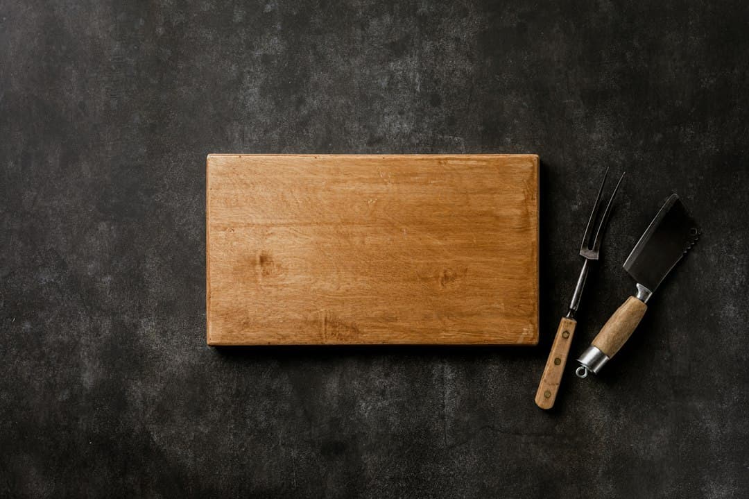 A wooden cutting board with a knife and fork