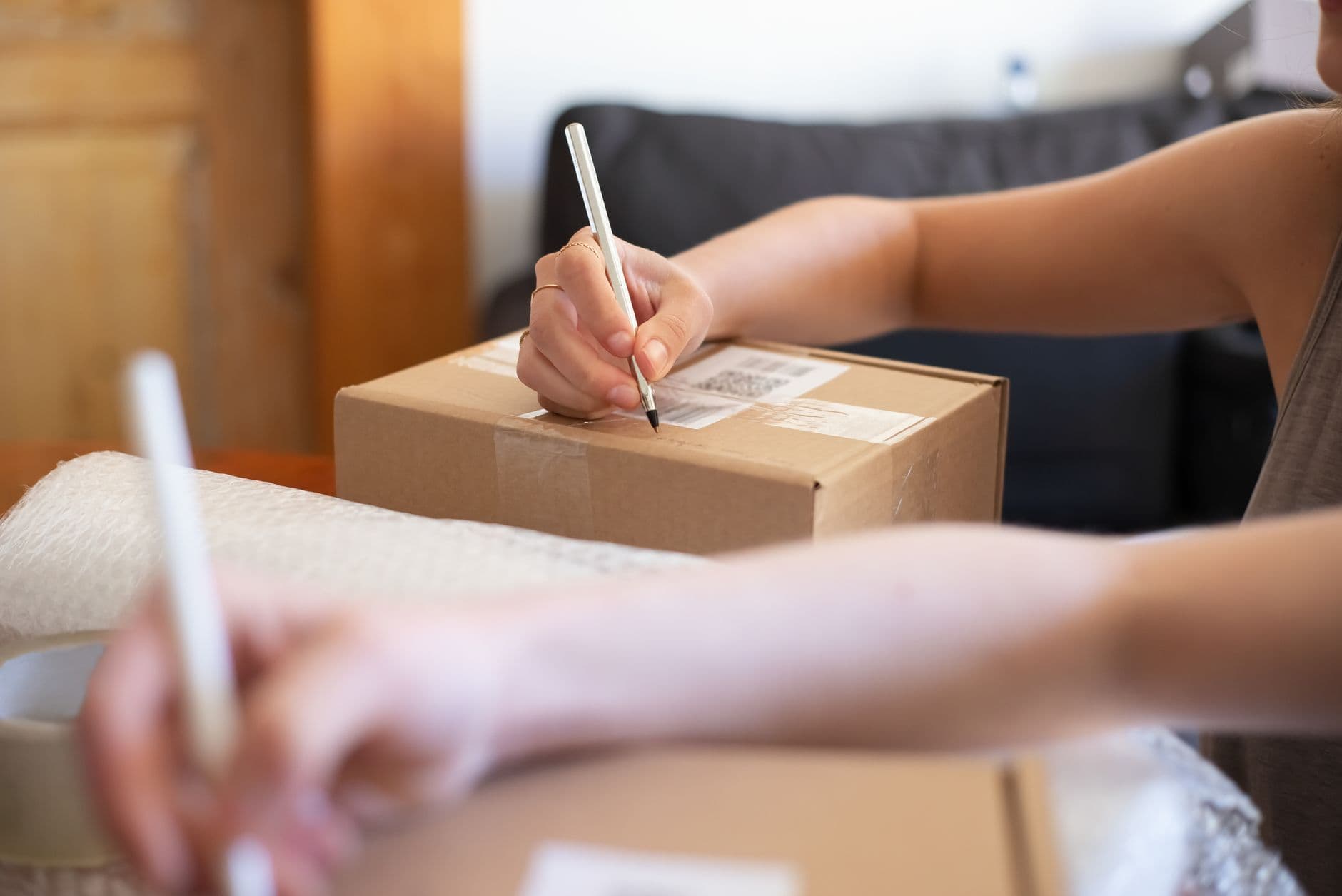 Hands labeling a cardboard box for shipping from a home office