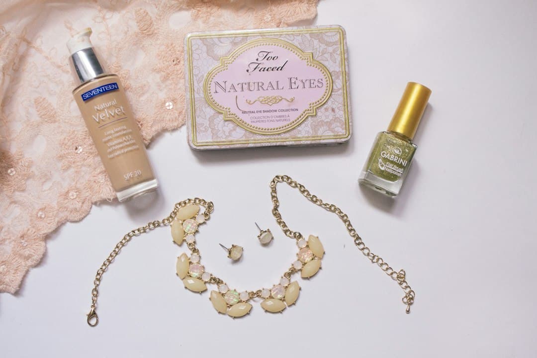 Cosmetics and a necklace arranged on a white table for a product photo
