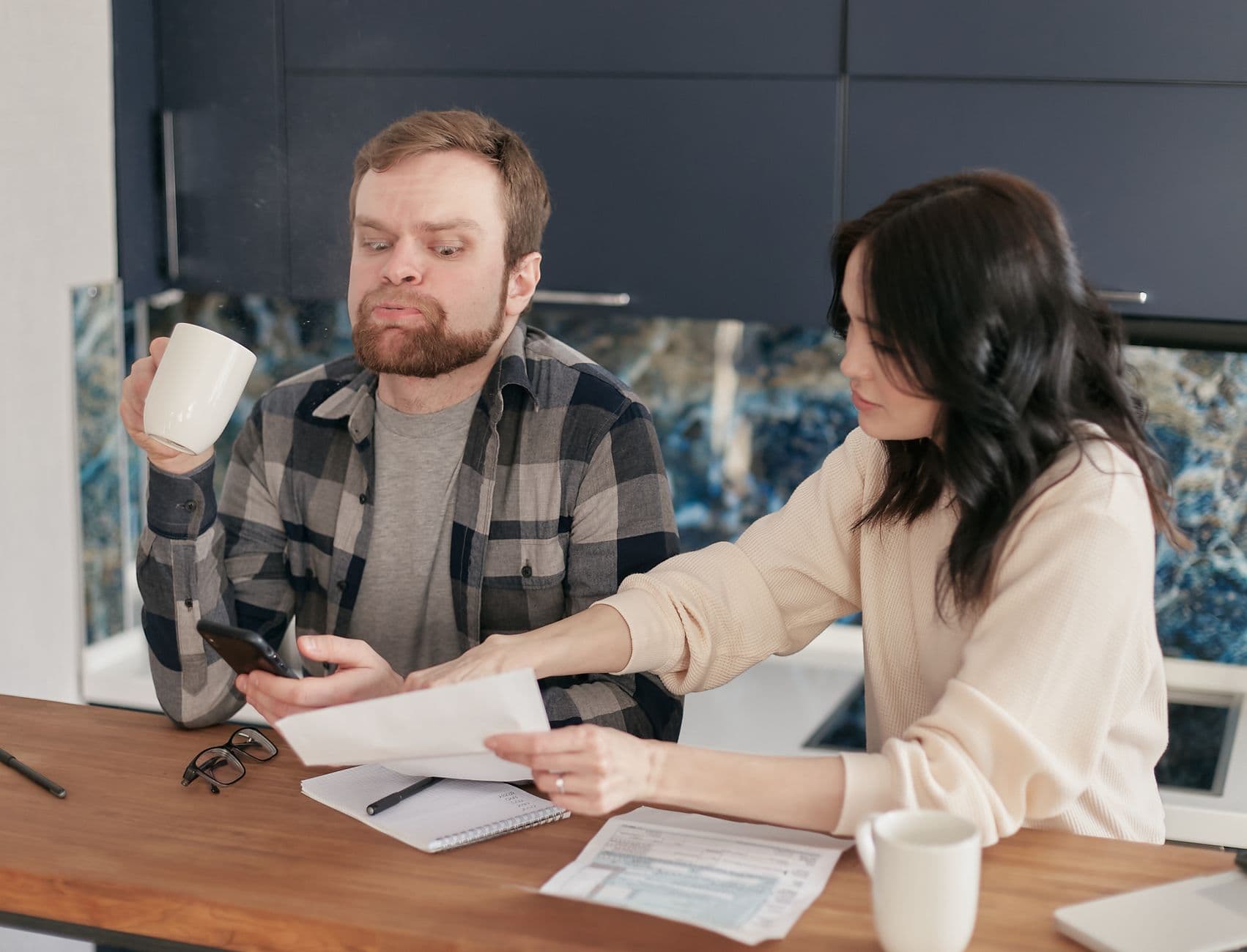 A worried couple reviewing bills at their kitchen table