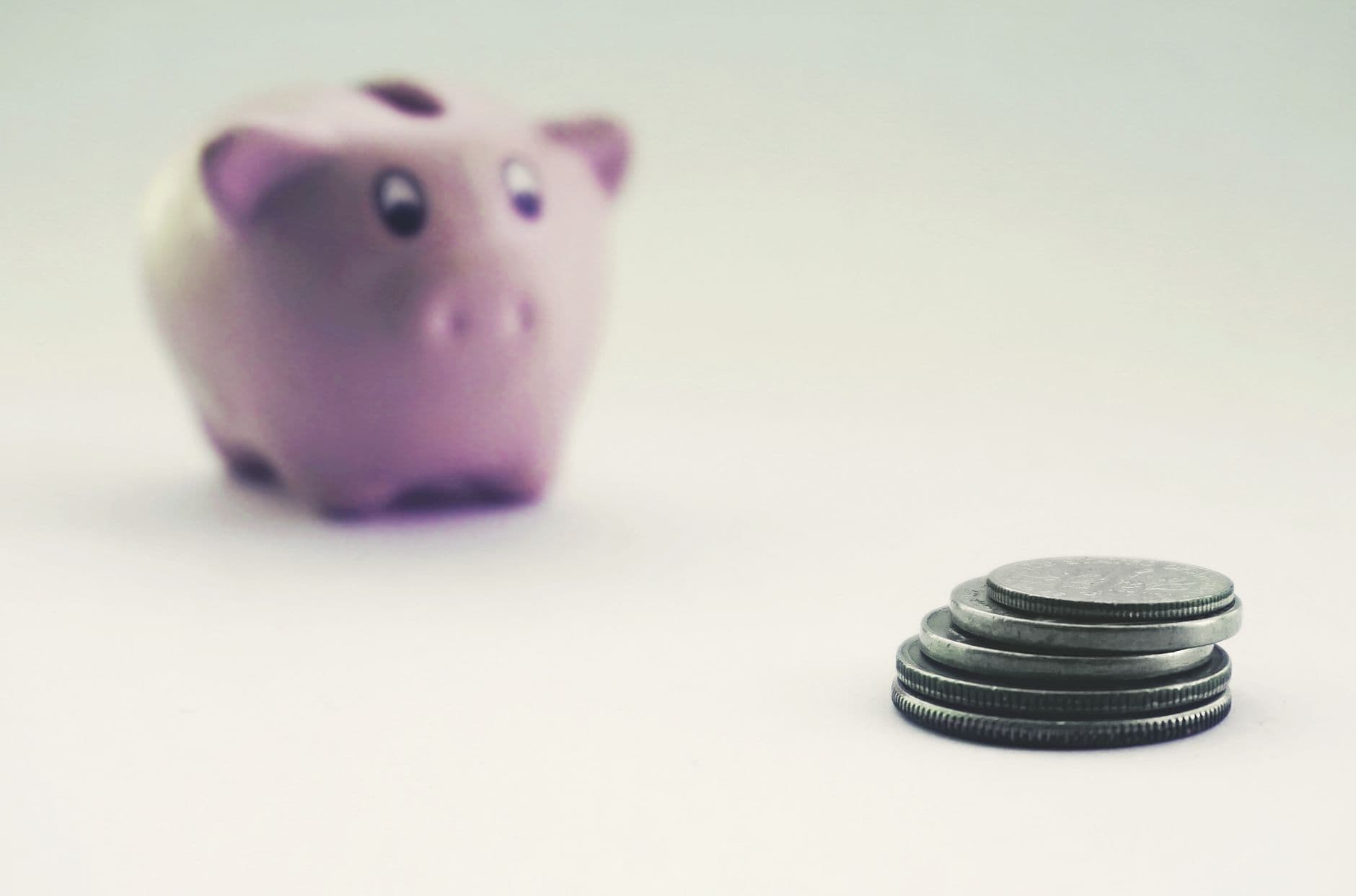 Stacked coins in front of a pink piggy bank