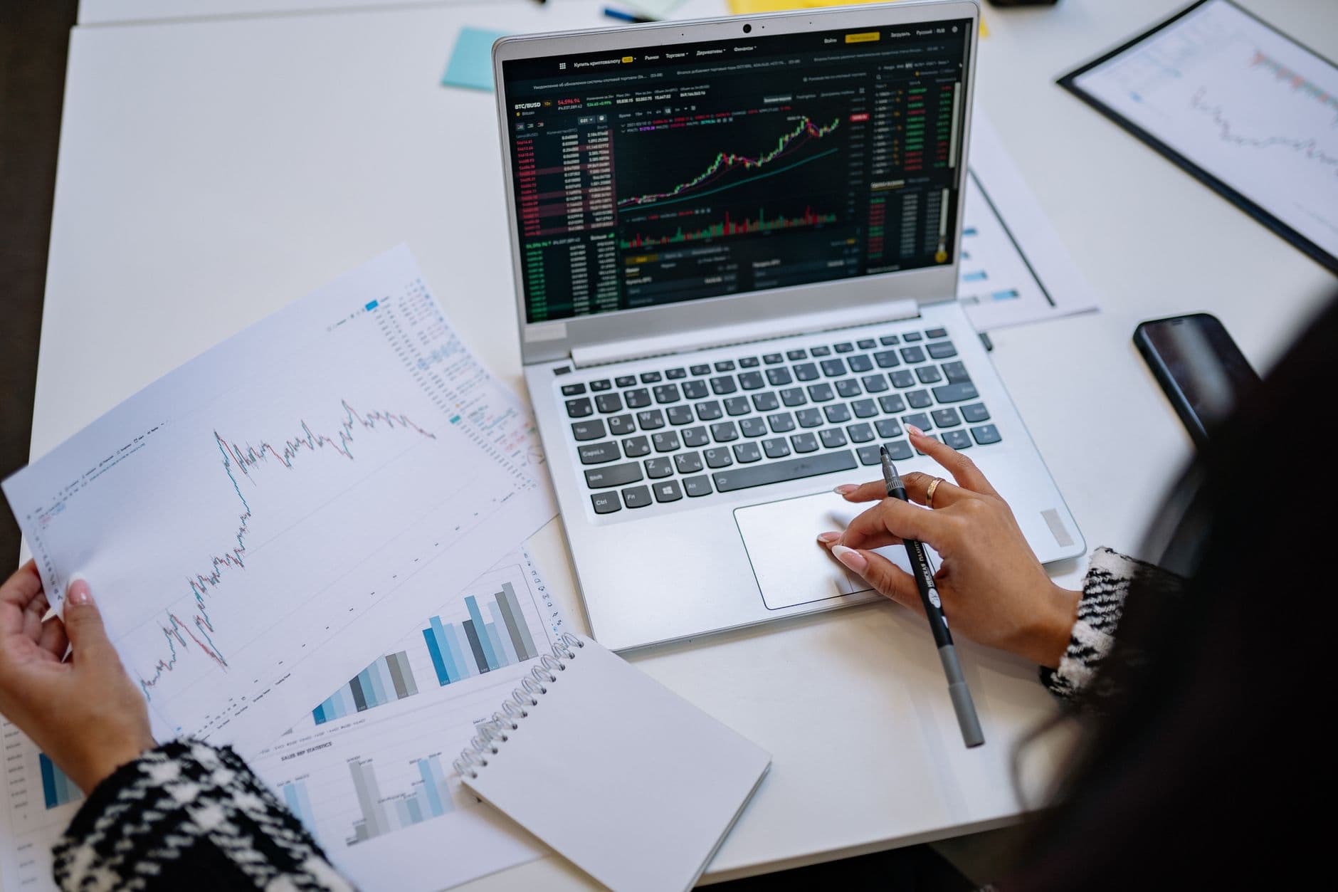 A laptop displaying financial charts and graphs on a table