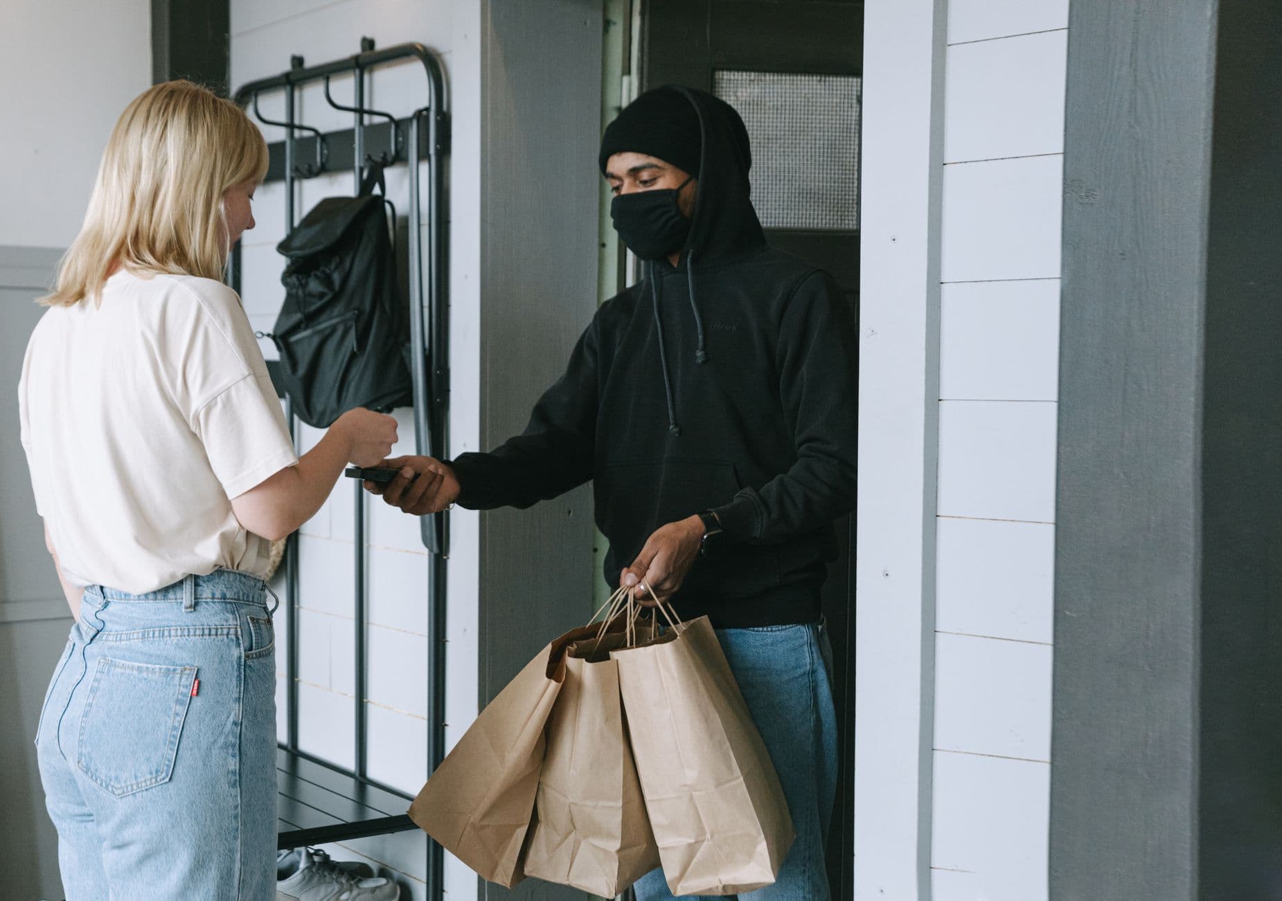 A delivery person handing paper bags to a customer at the door