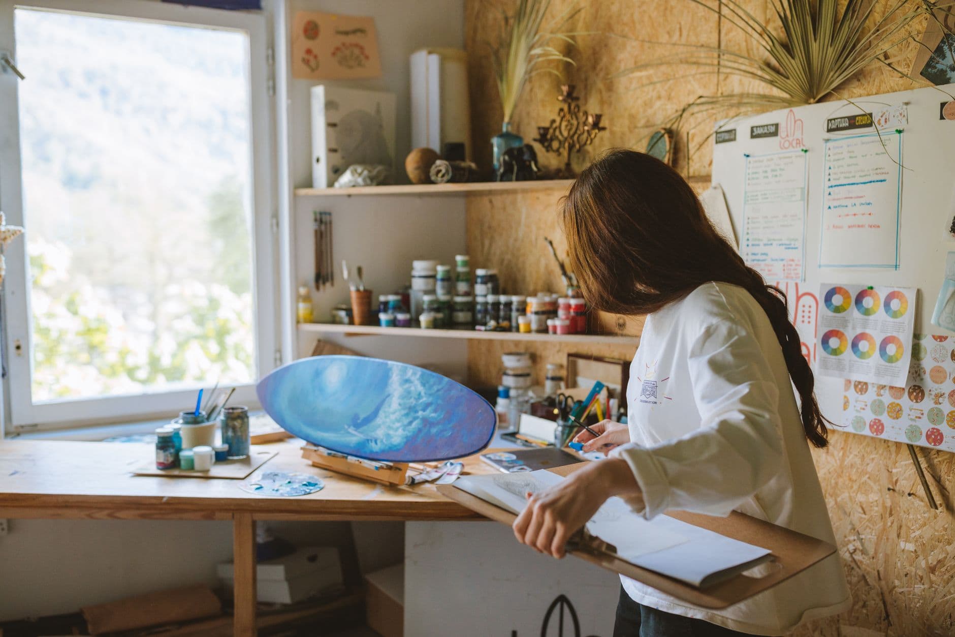 A woman artist painting an ocean scene in a cozy art studio