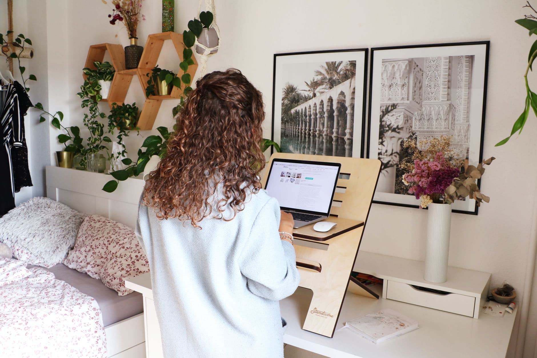 A woman using a laptop at a standing desk in her home office