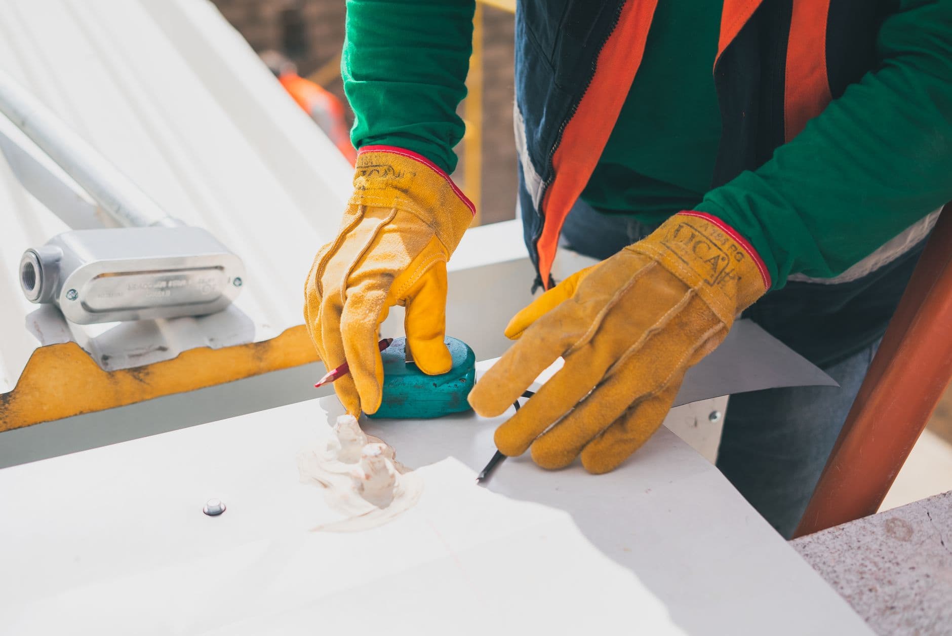 An electrician in protective gloves taking measurements on a rooftop