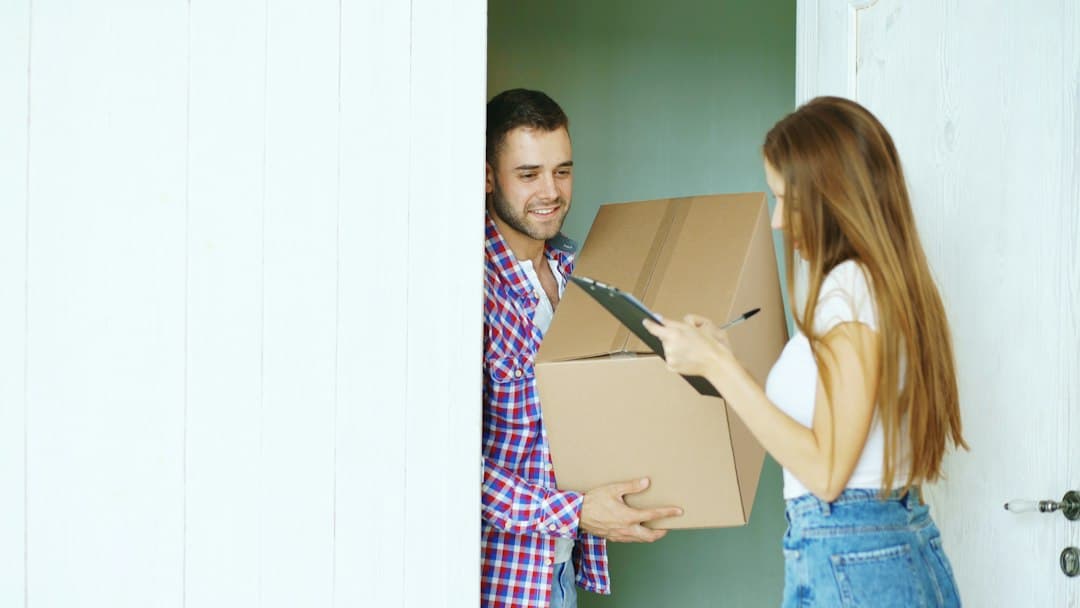 A couple signing for a package delivery at their door