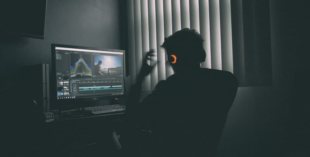 A person in headphones editing video on a computer in a dark room