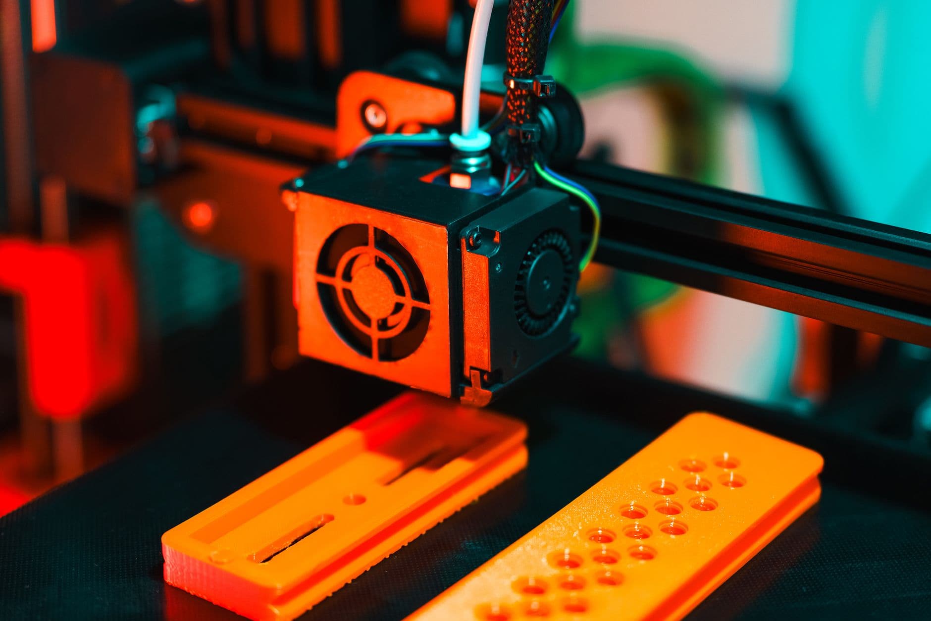 A 3D printer extruding orange plastic parts