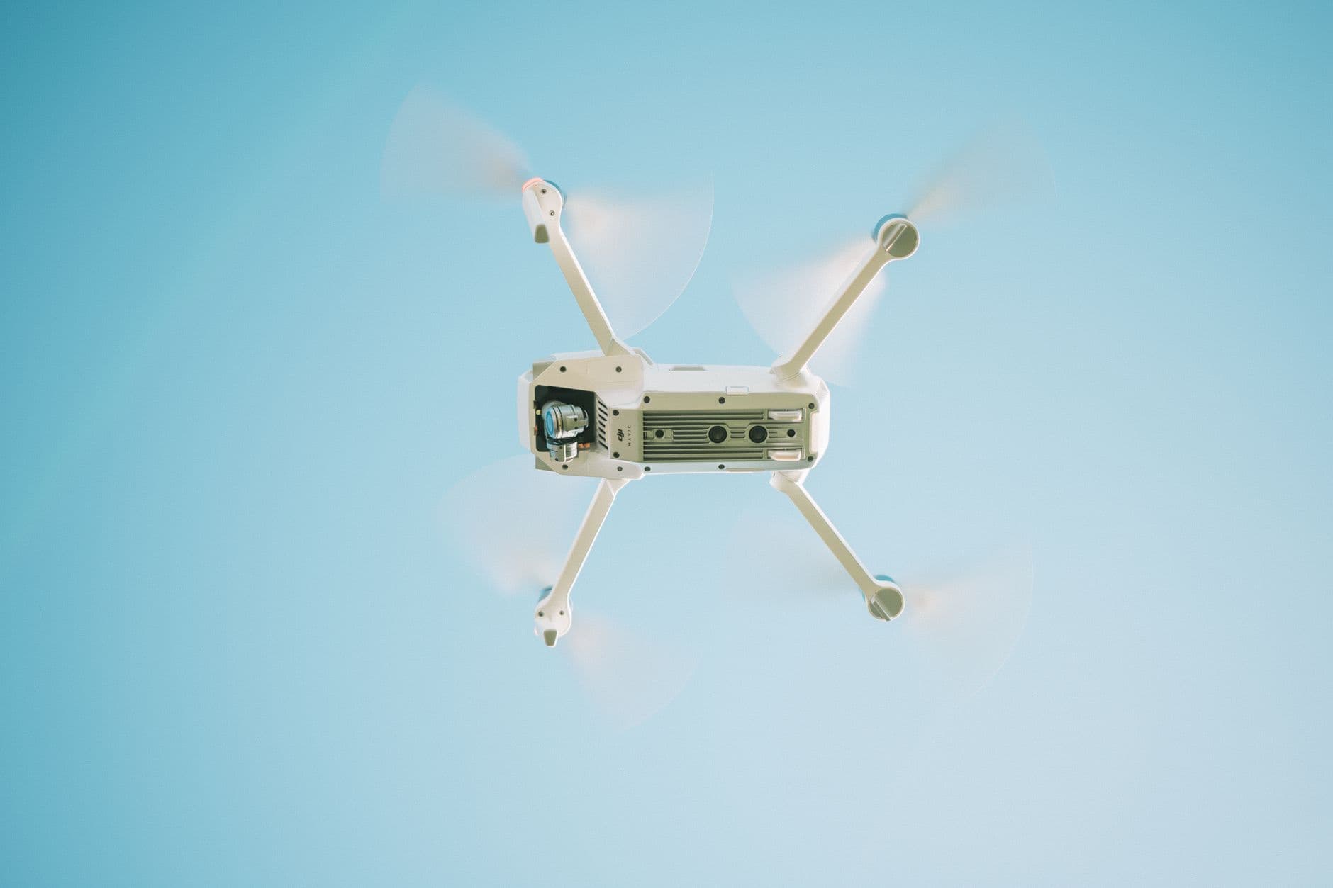 A white drone flying under a clear blue sky
