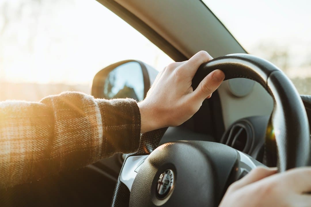 A person holding the steering wheel of a car