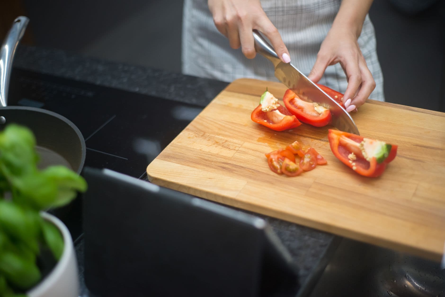 A woman slicing a red bell pepper in her kitchen