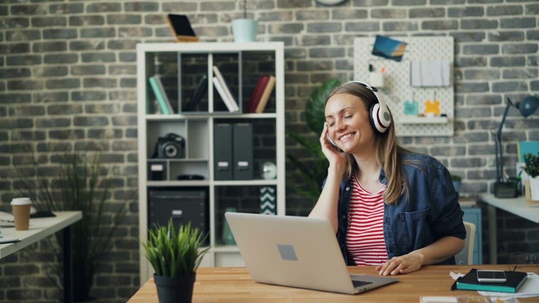 A woman wearing headphones sitting in front of a laptop