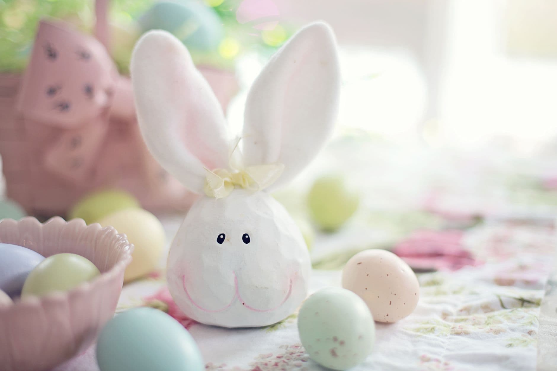 A bunny decoration with pastel eggs on a floral tablecloth