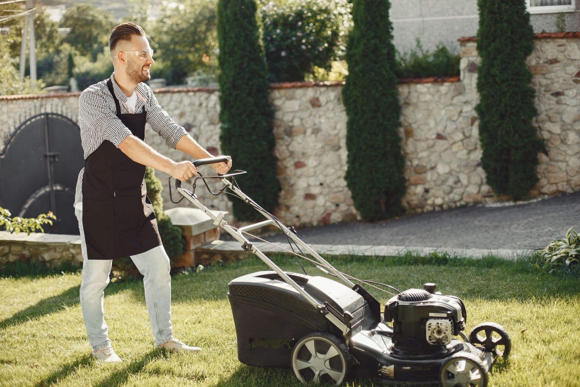 A man using a lawn mower in a sunny garden