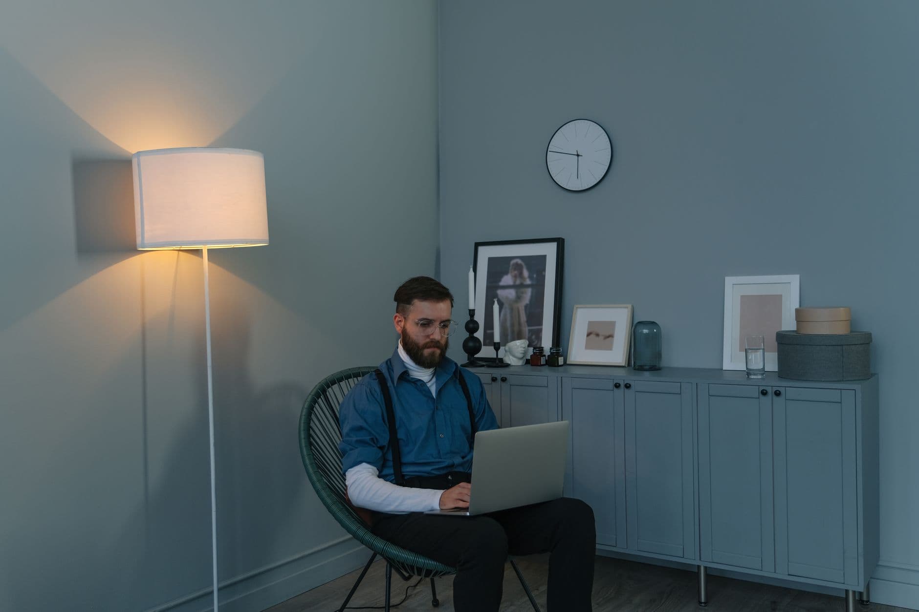 A man in a blue shirt working on a laptop in a home office