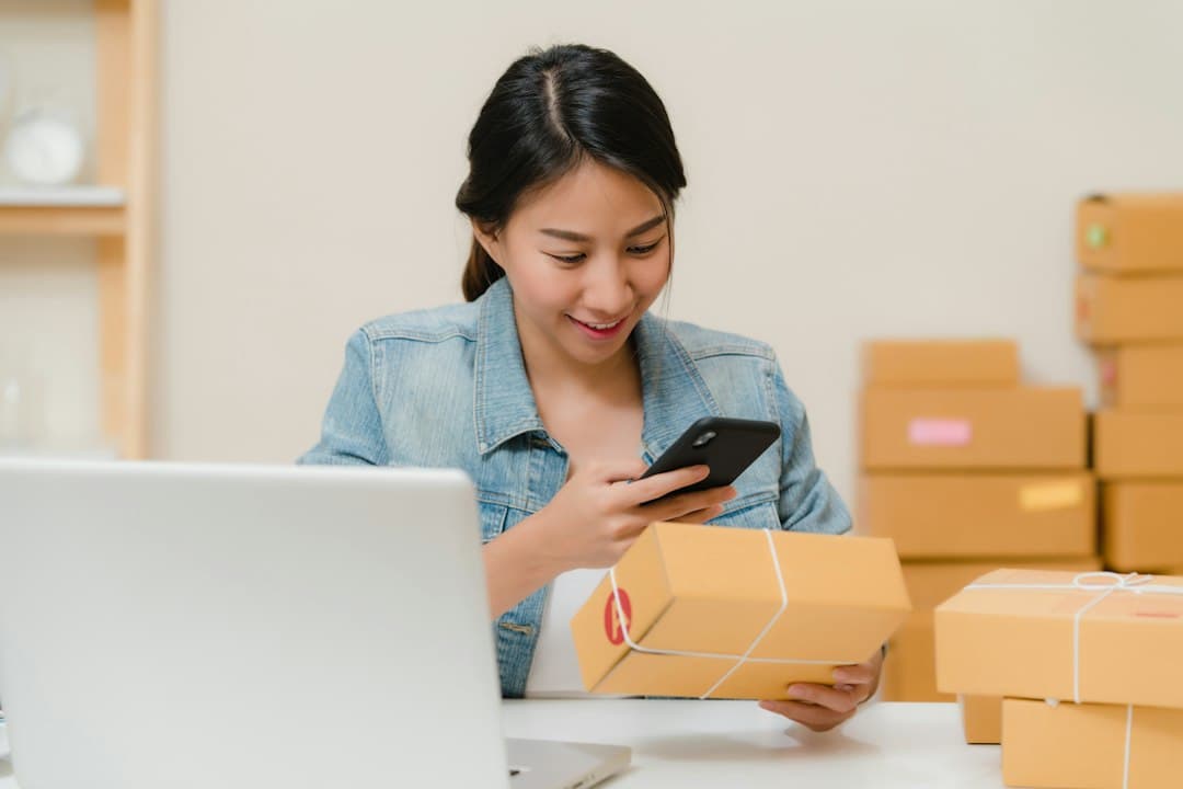 A woman checking a package next to her laptop and shipping boxes