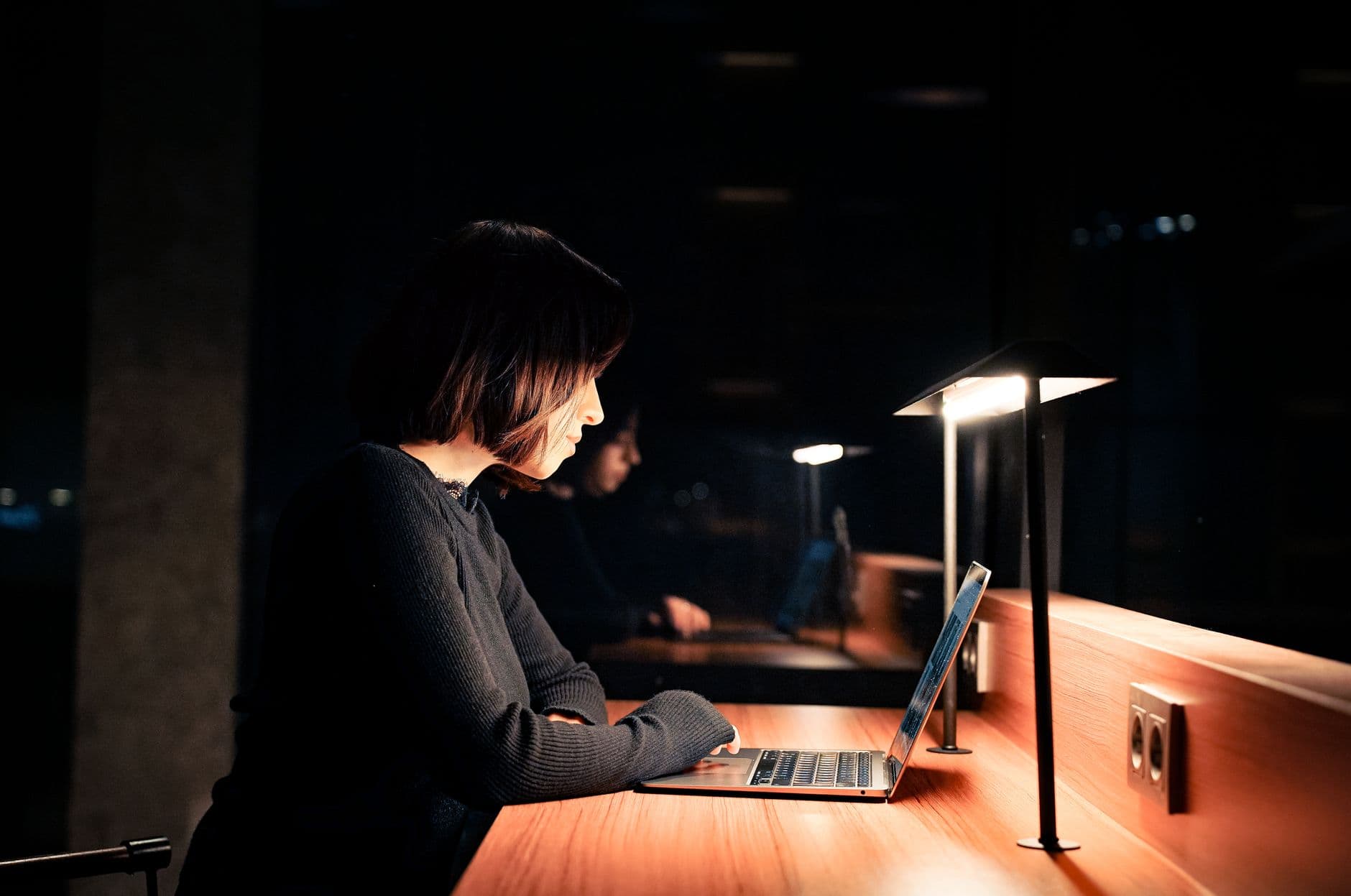 A woman working on her laptop at a desk late at night