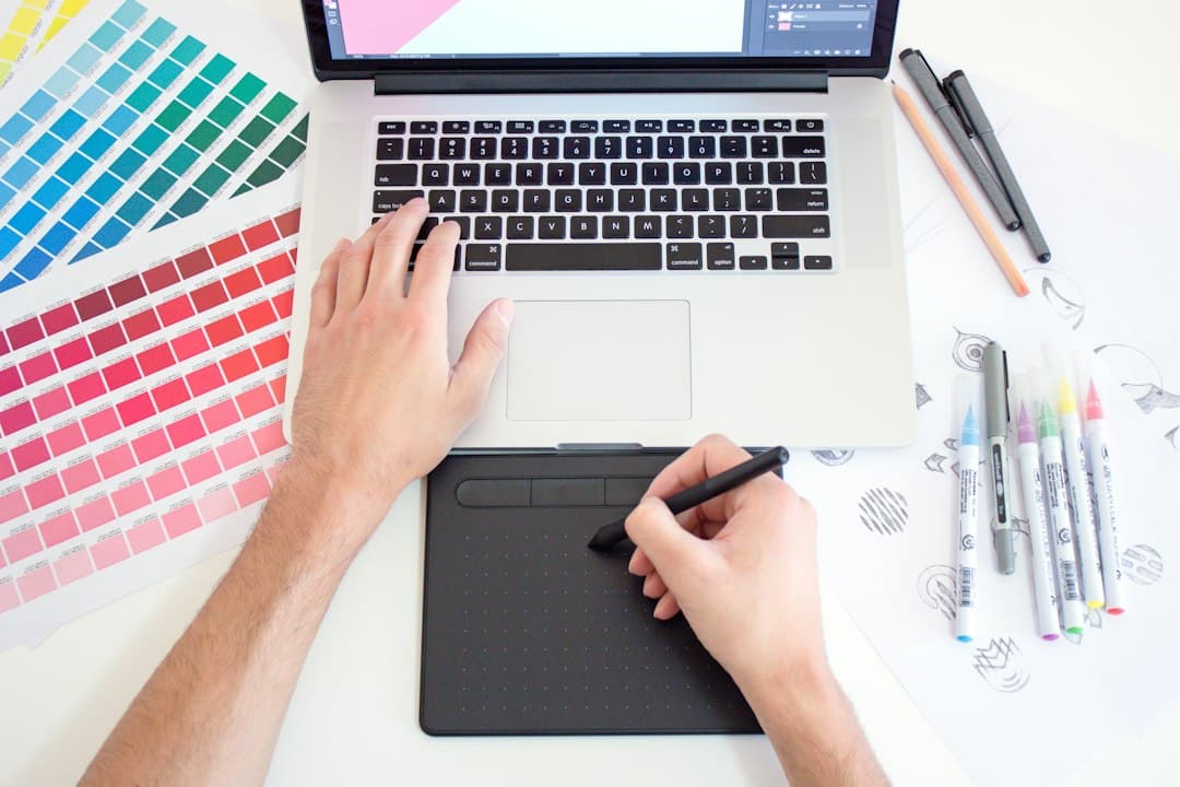 A person using a drawing tablet and laptop with color swatches