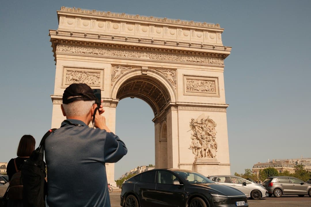 A tourist photographing the Arc de Triomphe in Paris