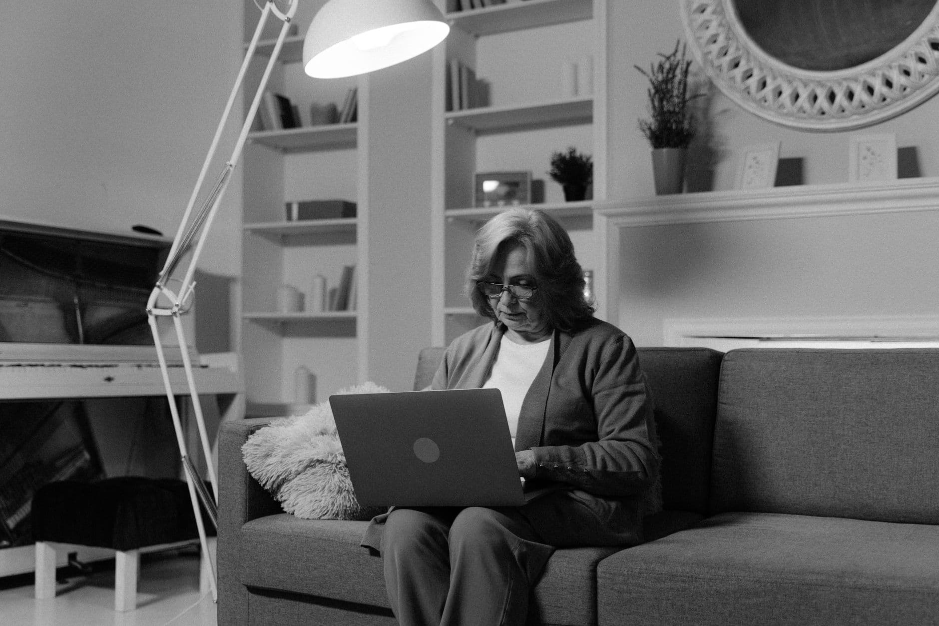 An older woman using a laptop on a couch in her living room