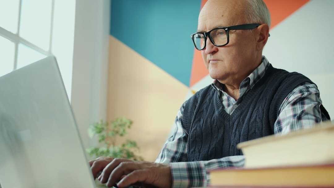An older man with glasses using a laptop